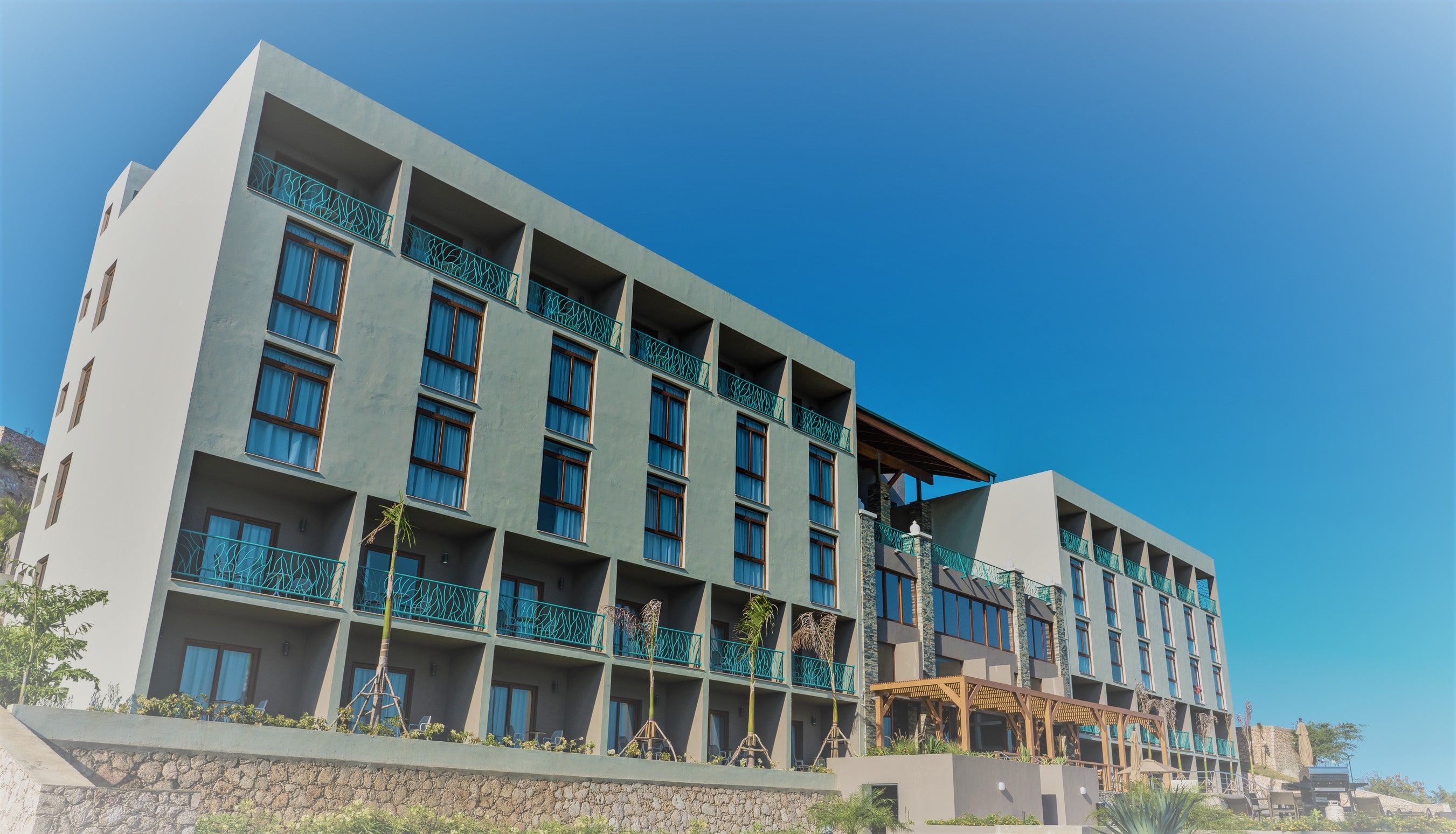 Satama Hotel, with balconies facing the bay, under a blue sky