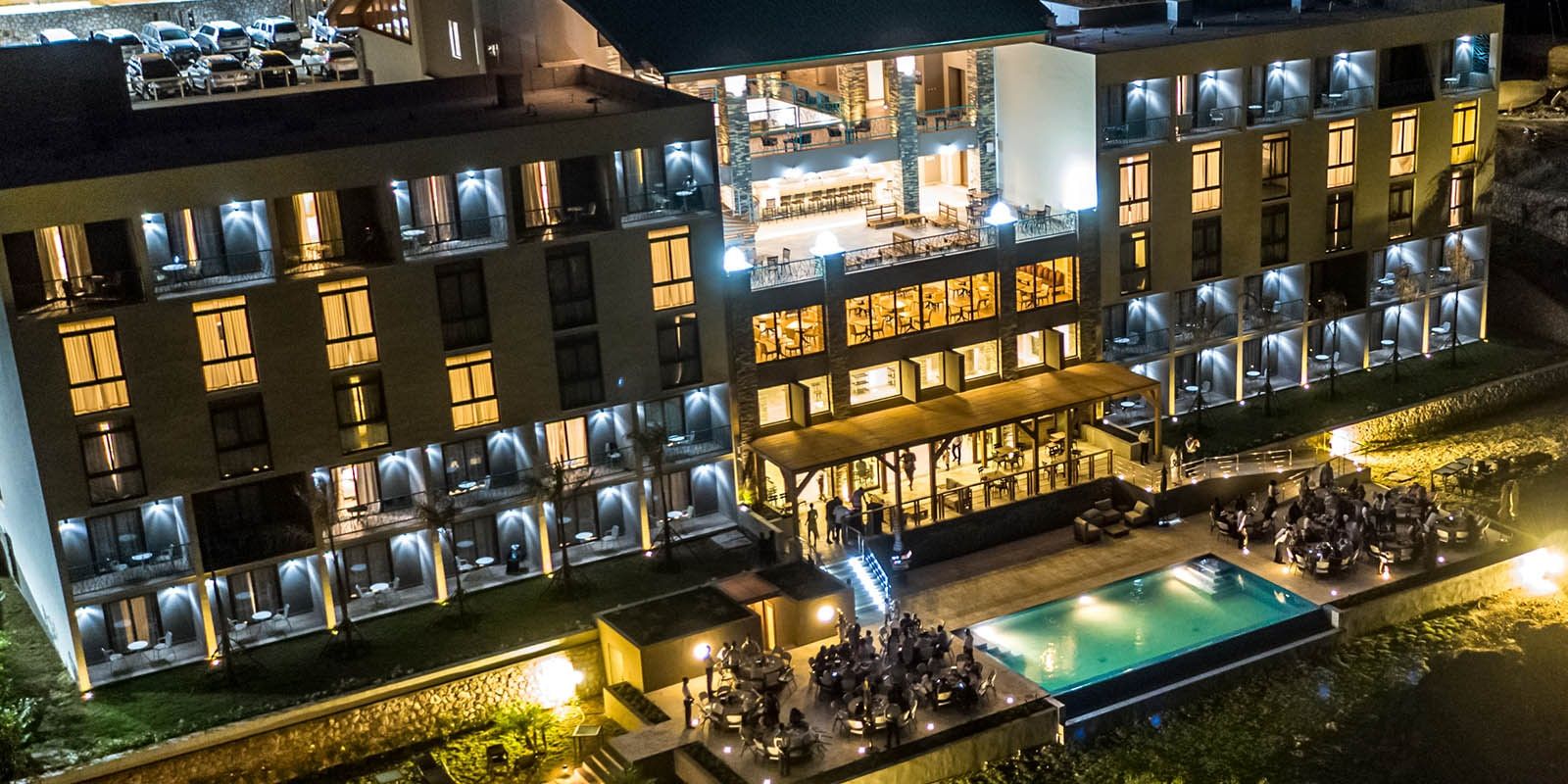 Satama Hotel lit up at night, with the pool and terrace